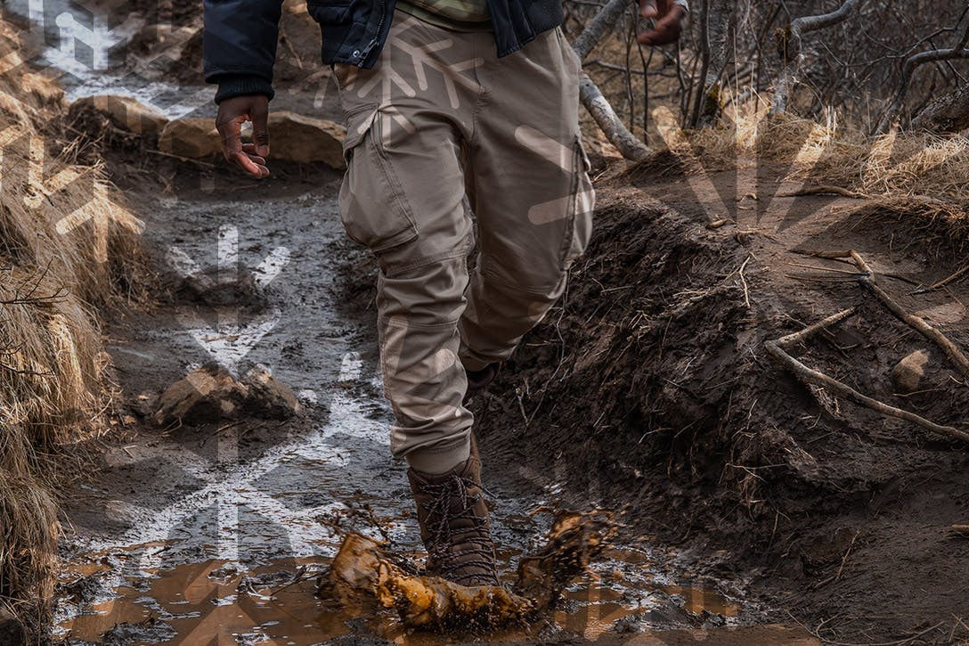 Man jumping in a mud puddle wearing waterproof Oboz hiking boots
