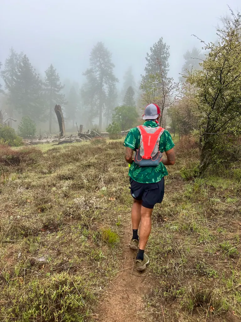 A long-distance hiker moves along a misty trail in Oboz fast trail shoes