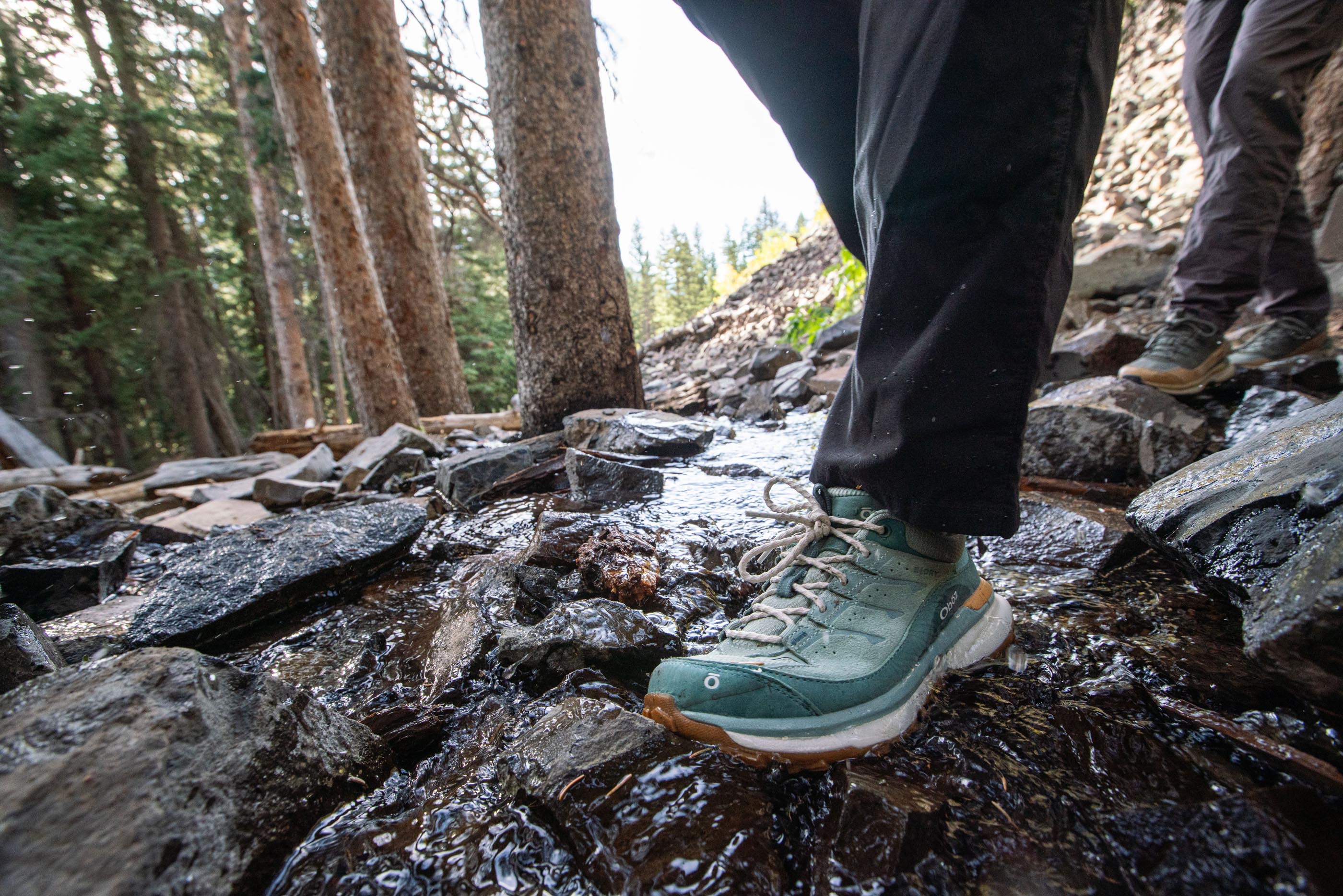 Walking across a stream in the women's waterproof Oboz Hyalite hiking shoes.