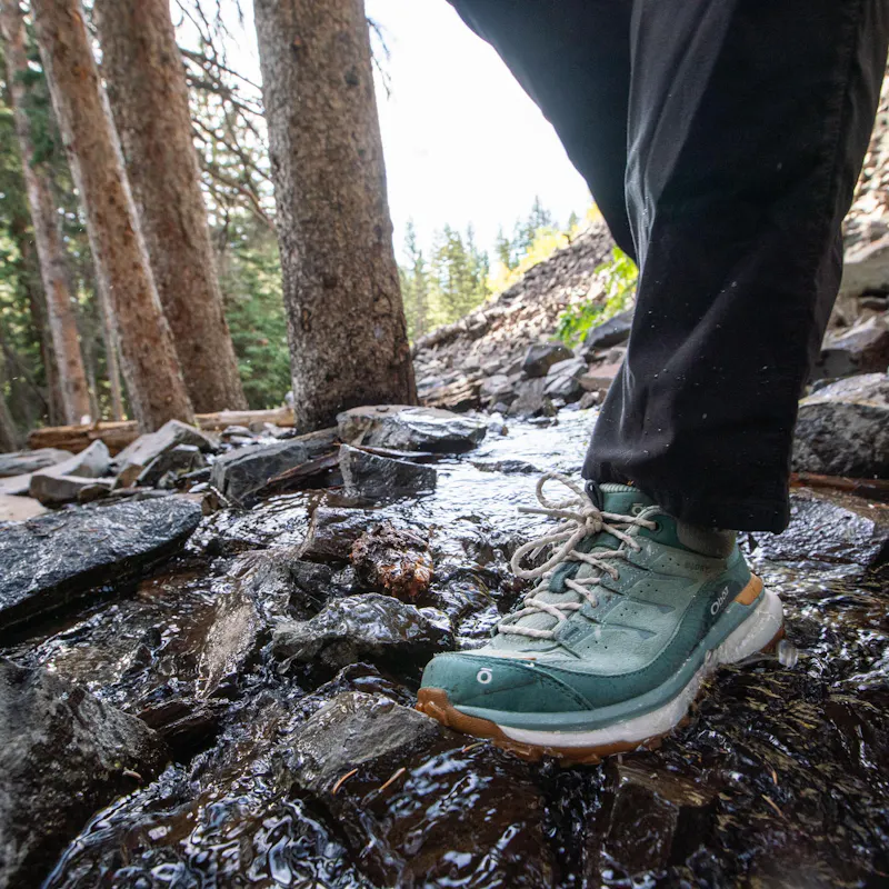 Walking across a stream in the women's waterproof Oboz Hyalite hiking shoes.