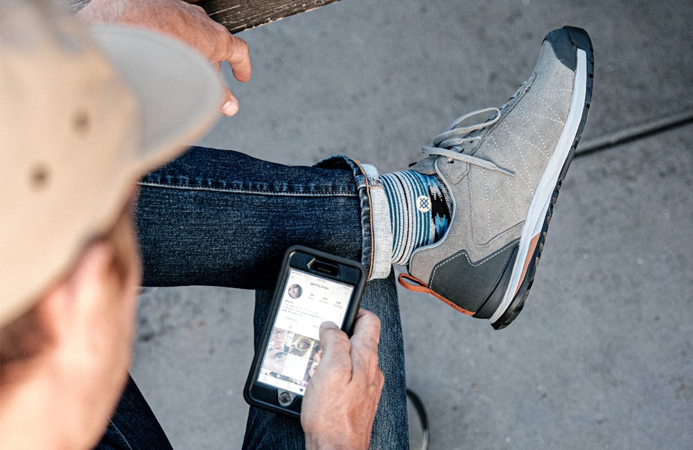 Robin Hill scrolling Instagram in Bozeman Low Leather casual shoes.
