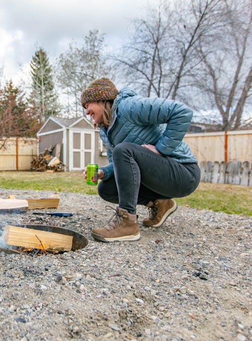 A couple prepares a campfire in their backyard while staying warm in Oboz winter boots.