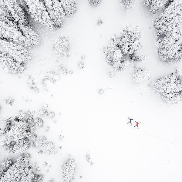 Drone shot of two happy hikers doing snow angels.