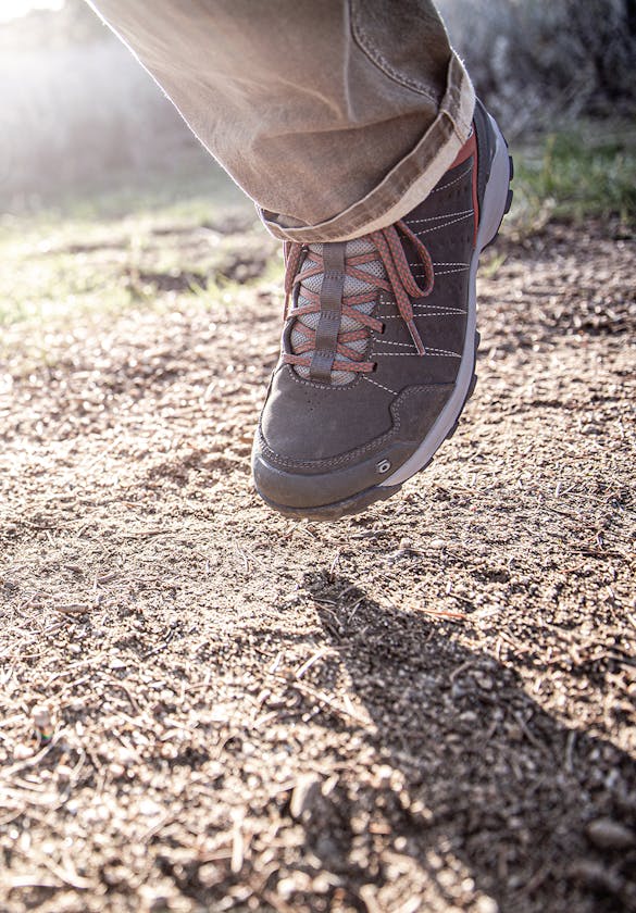 A hiker walking in the Oboz Men's Sypes Low Leather Waterproof casual shoes on the trail