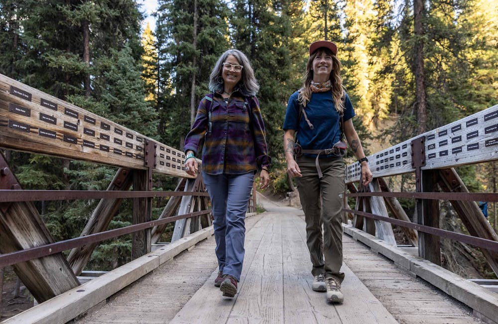 Two women crossing a wooden bridge in Oboz Ousel hiking boots