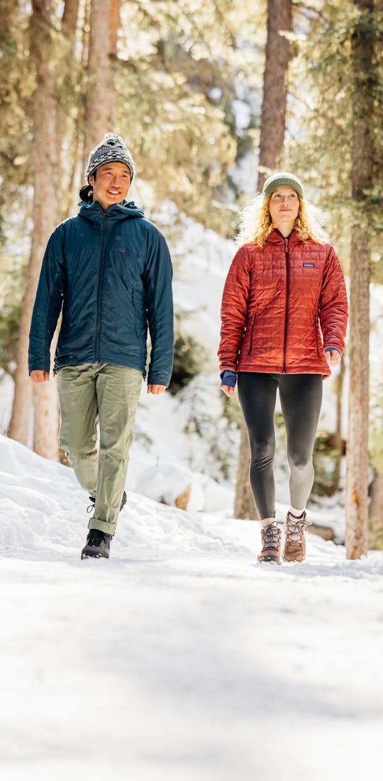 A couple hiking in the snowy woods in Oboz winter boots