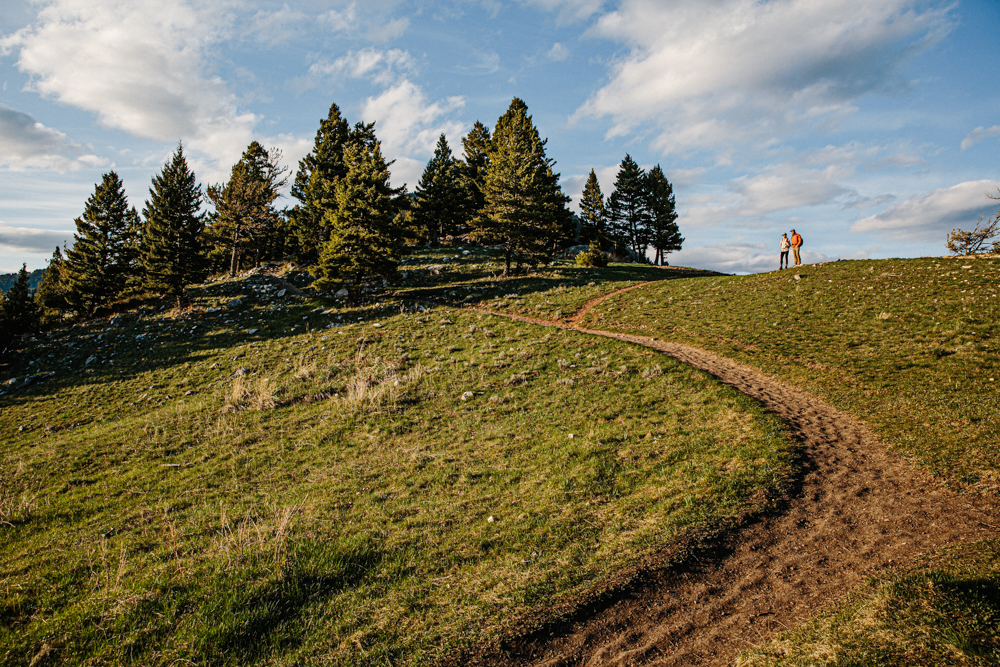 Two hikers wearing Oboz hiking shoes stopped at a fork in the trail on a sunny day