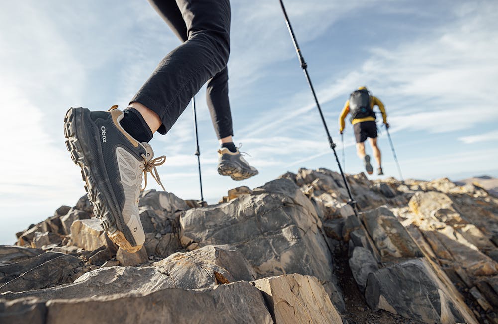 A man and woman climbing up mountain terrain in Oboz Katabatic hiking shoes