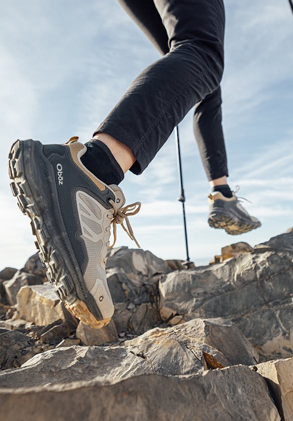 Woman climbing up steep rocky terrain in Oboz Katabatic hiking shoes