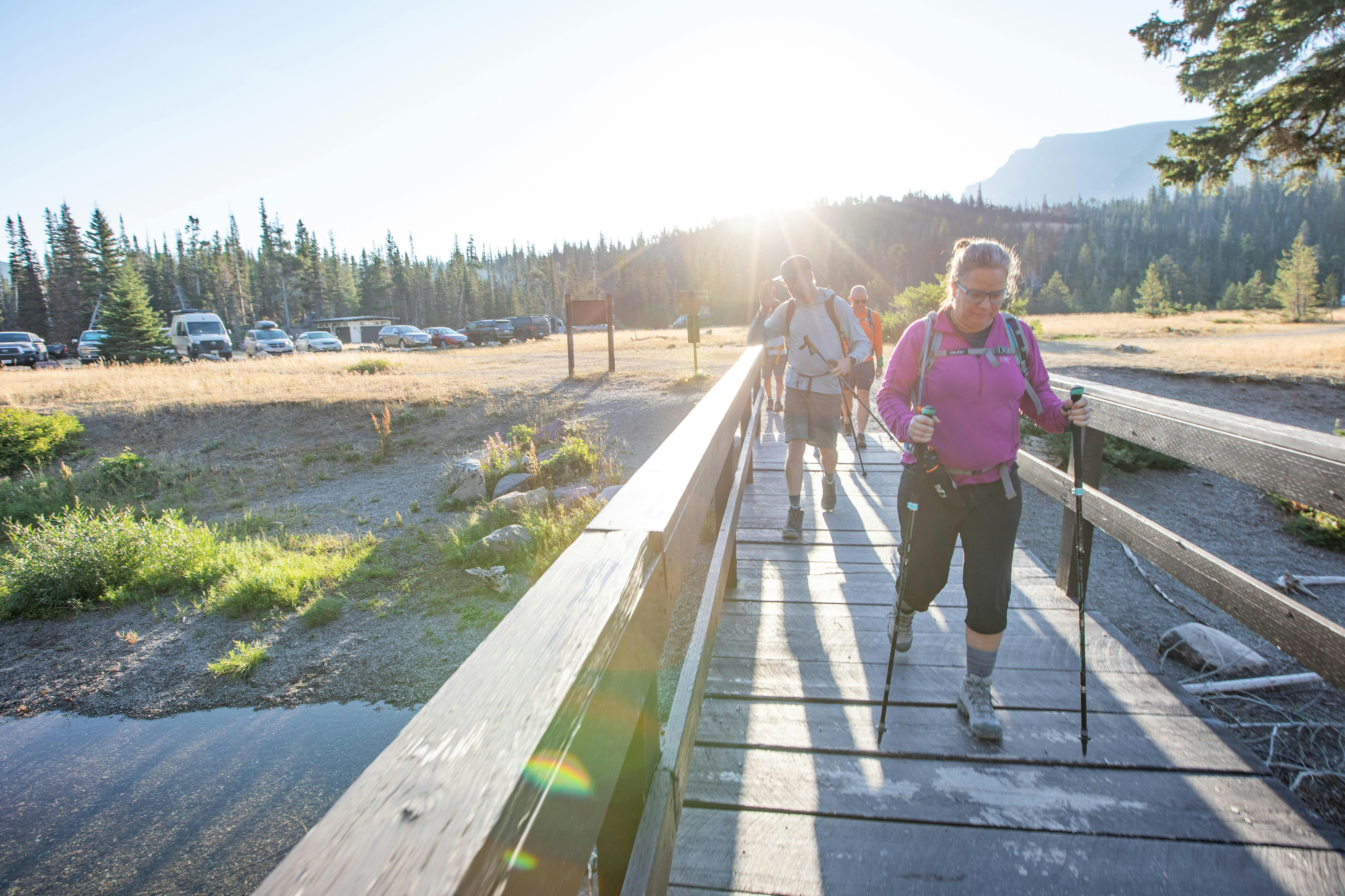 Many hikers cross a bridge at the beginning of trail wearing their Oboz hiking shoes