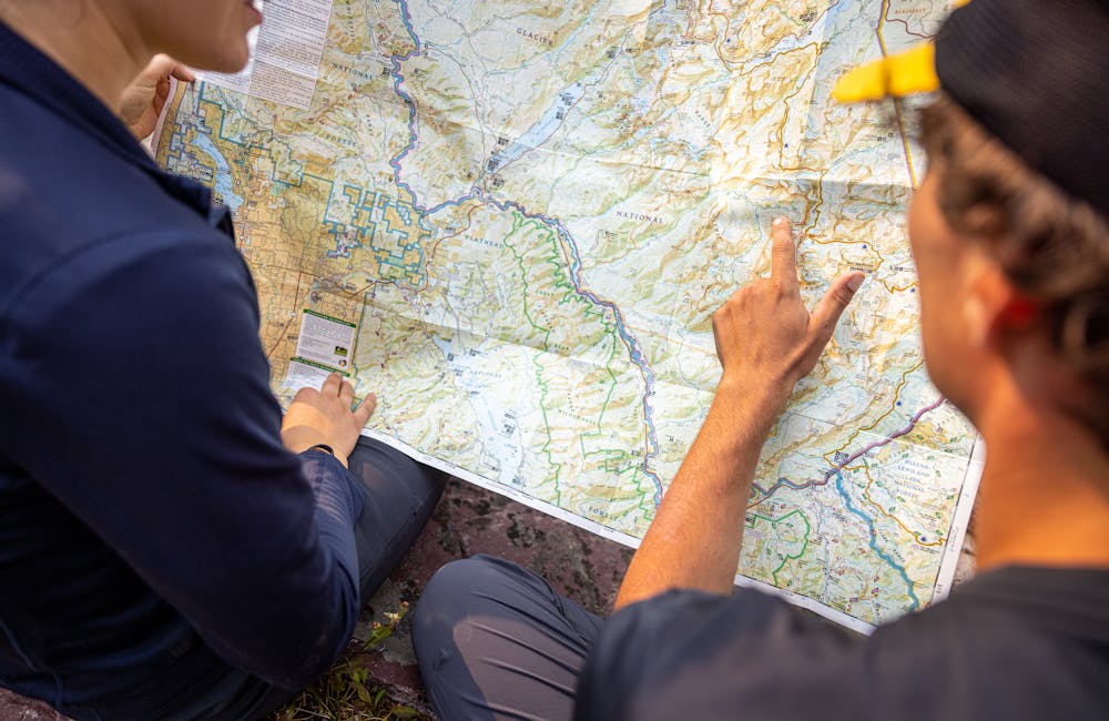 Two backpackers planning their hike on a physical map.