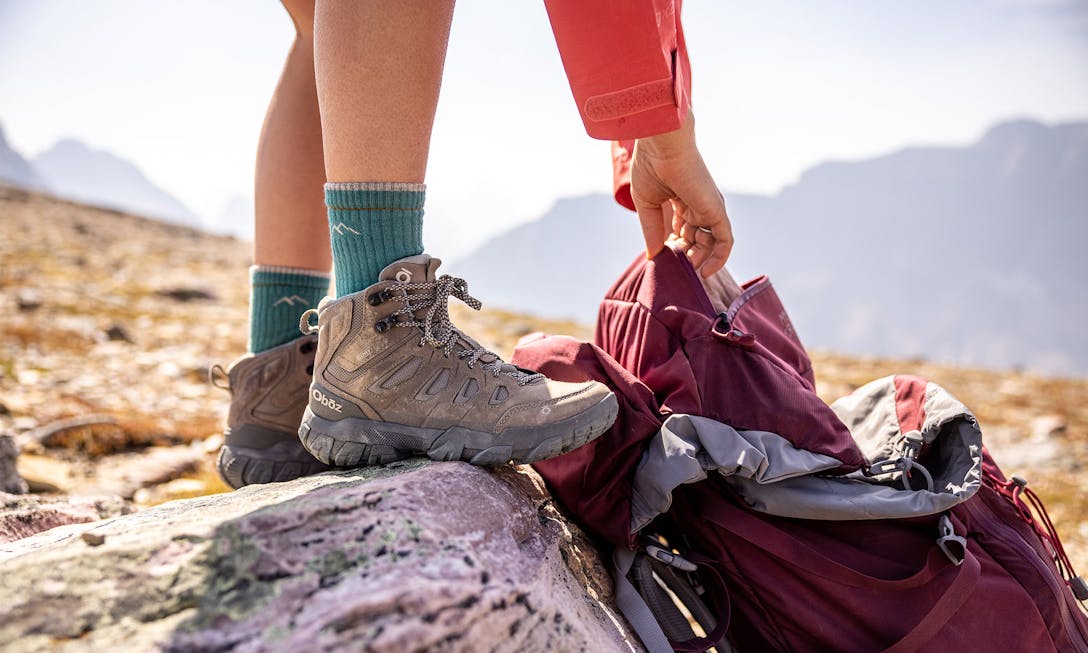 Hiker in an Oboz Sawtooth X mid height hiking shoe adjusting their backpack. 