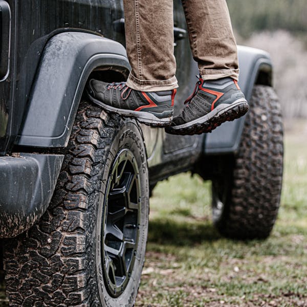 Overlander standing on a jeep tire in the Oboz Sypes Mid Leather hiking boot.
