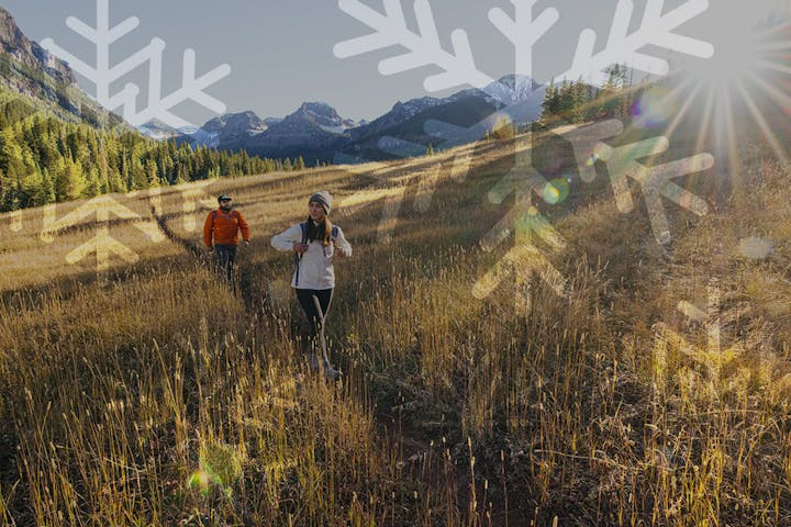 Two hikers hiking in a mountain meadow while wearing Oboz hiking boots