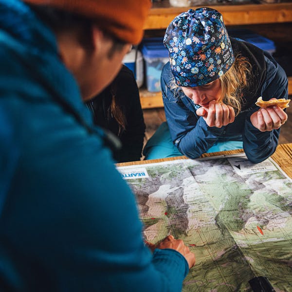 Planning the day over a map in the Oboz and Skida Whakatā running hat.