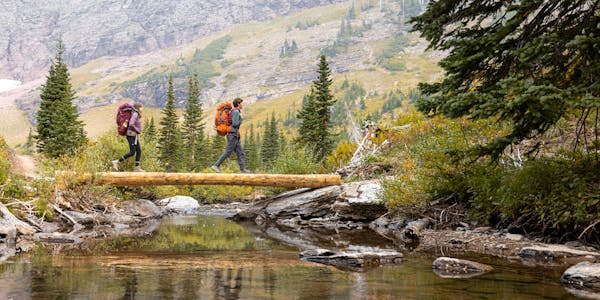 Two hikers crossing a mountain stream while wearing Oboz Sawtooth X hiking boots