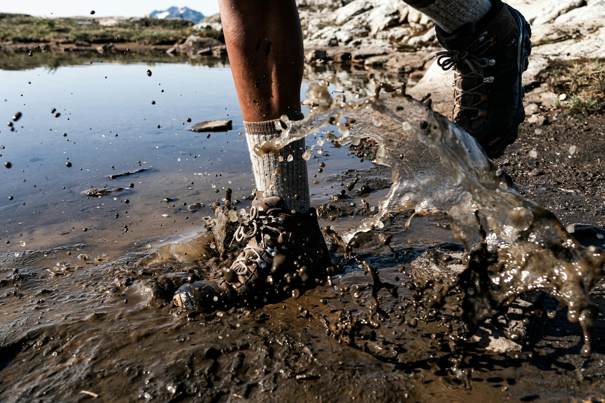 Hiker stepping through deep muddy puddle in a pair of Sudan Oboz Bridger Mid Waterproof Boots