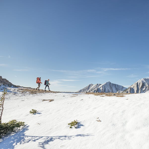 Two people wearing the Bridger Mid Waterproof hiking boots in the snowy high alpine.