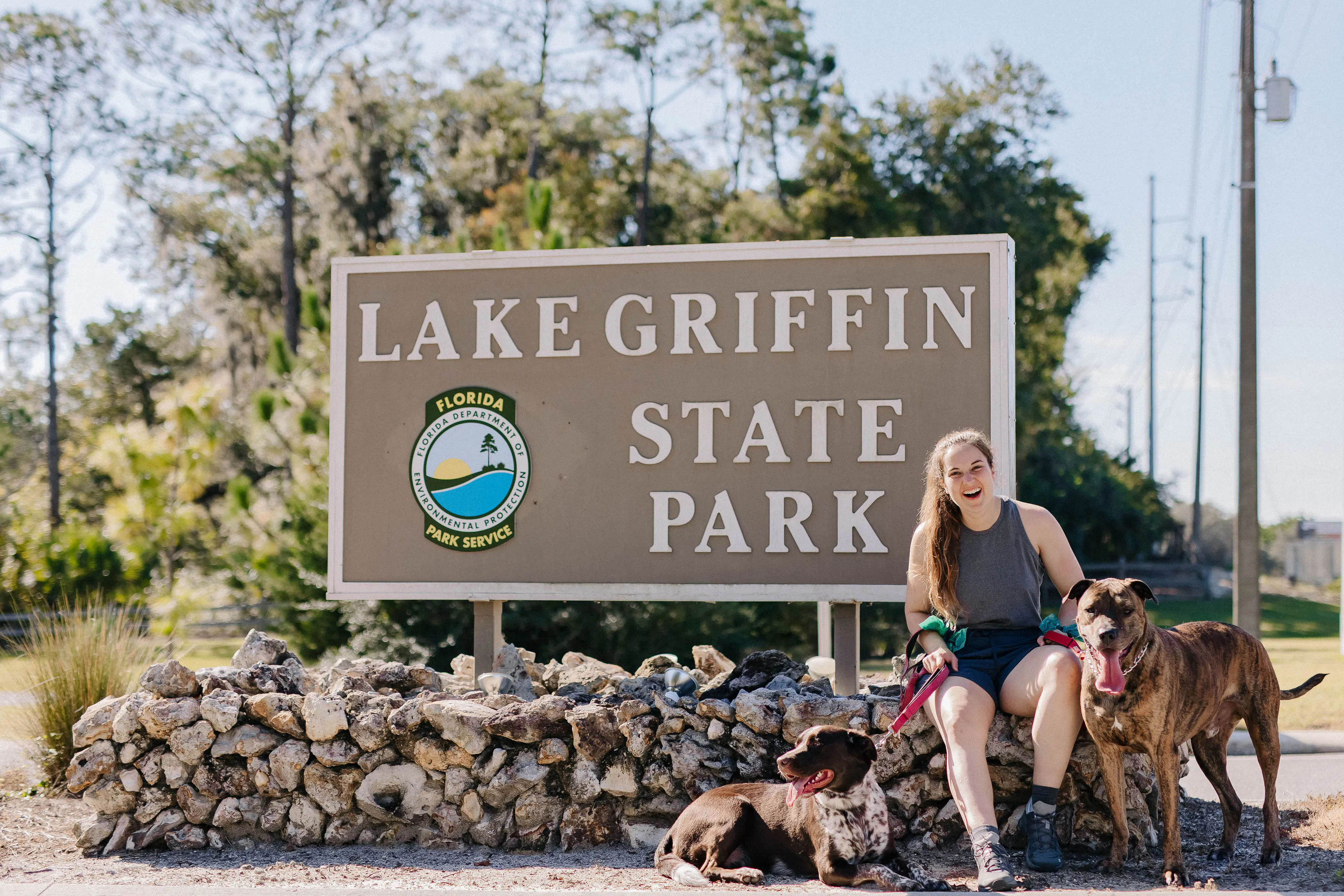 Woman and two dogs in front of the Lake Griffin State Park sign
