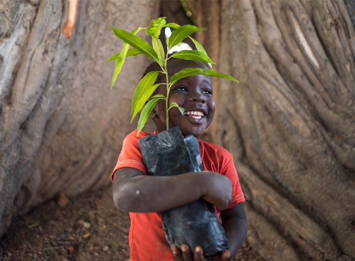 Boy holding saplings as part of the Oboz Footwear One More Tree program.