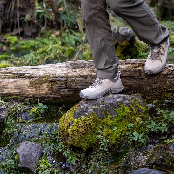 Oboz Ousel Low hiking shoe stepping on mossy rocks.