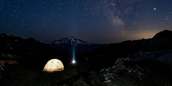 Tent camping under the stars in the wilderness after a long hike.