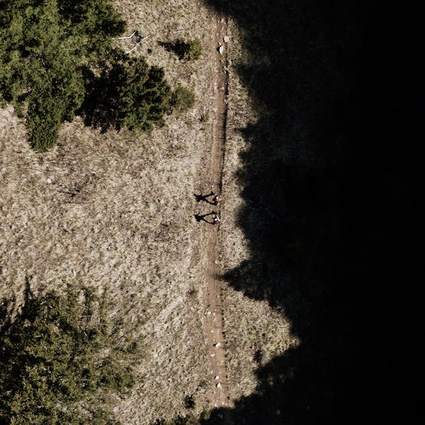 Aerial view of two hikers on a trail in the mountains.