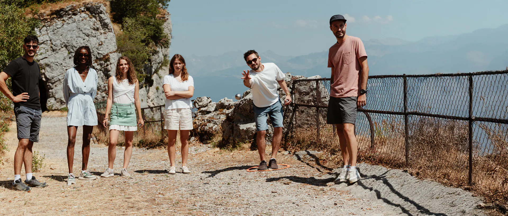 Groupe d'amis jouant à la pétanque en plein air avec une vue sur la montagne