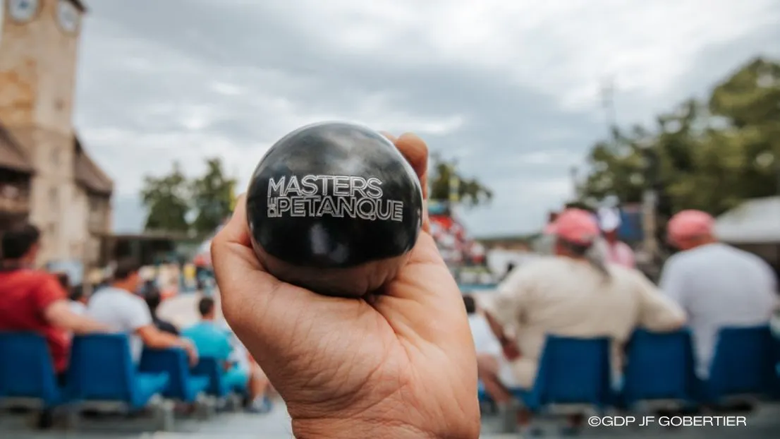 Une boule de pétanque Obut dans une main avec la personnalisation du logo des Masters de Pétanque