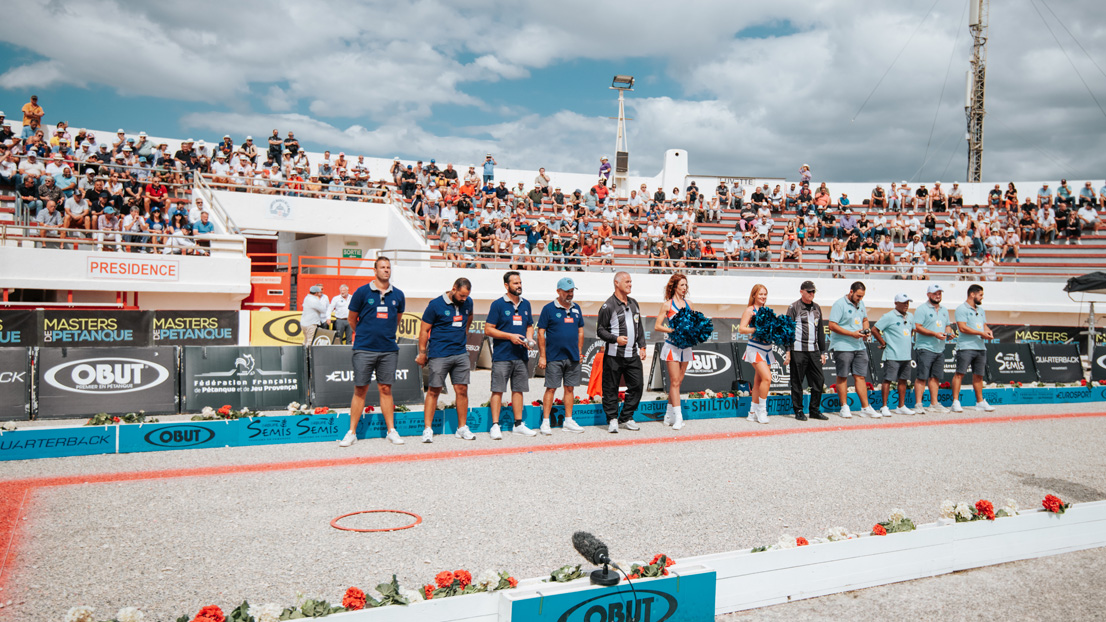 Deux équipes de joueurs de pétanque avec un arbitre sur un terrain suite à une compétition