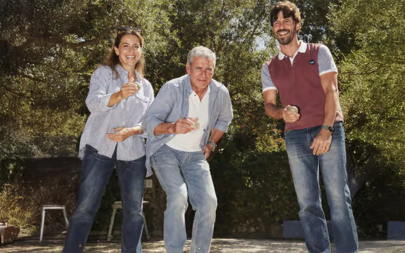 Trois personnes jouant à la pétanque et lançant des boules sur un terrain
