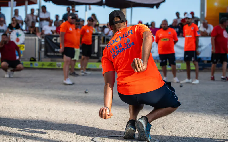 Joueur lançant une boule de pétanque lors d’une partie sur un terrain