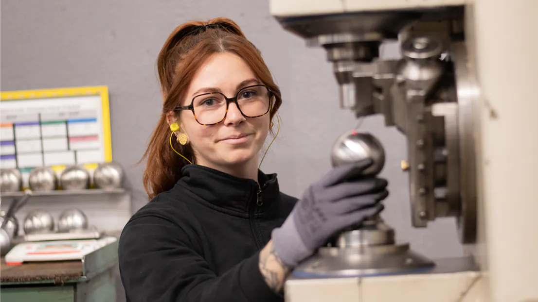 Amaurie, agente de production Obut positionnant une boule de pétanque dans les ateliers Obut