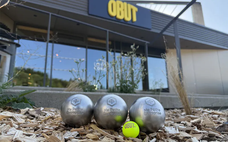 Une triplette de boules de pétanque, personnalisée Ma Petite Entreprise, posée devant l'entrée de l'entreprise La Boule Obut