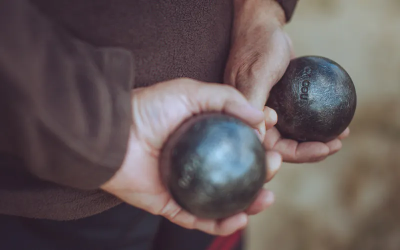 Homme ayant une boule de pétanque dans chacune de ses mains