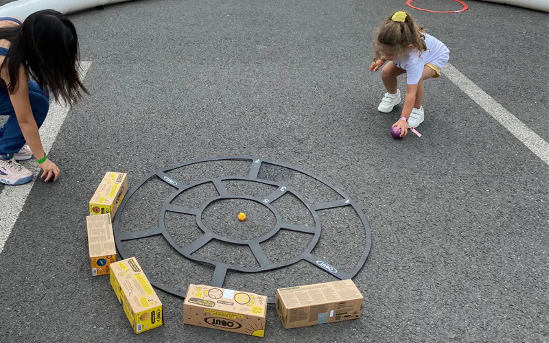 Two young girls taking part in a pétanque workshop during the Gulli Tour