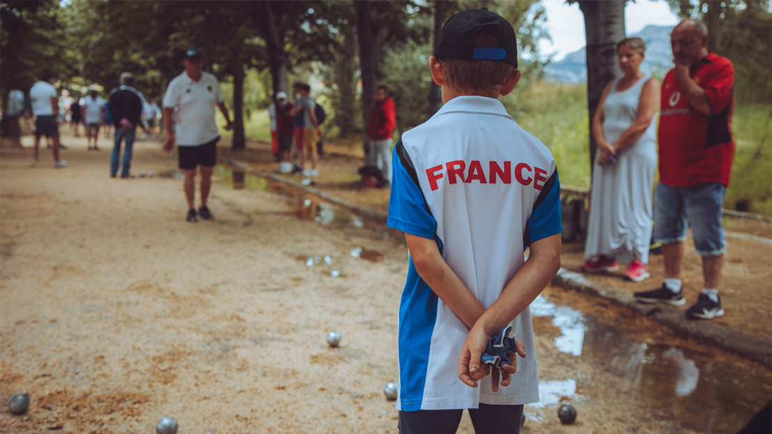 Ein Kind spielt bei einer Veranstaltung gemeinsam mit einem Erwachsenen Pétanque