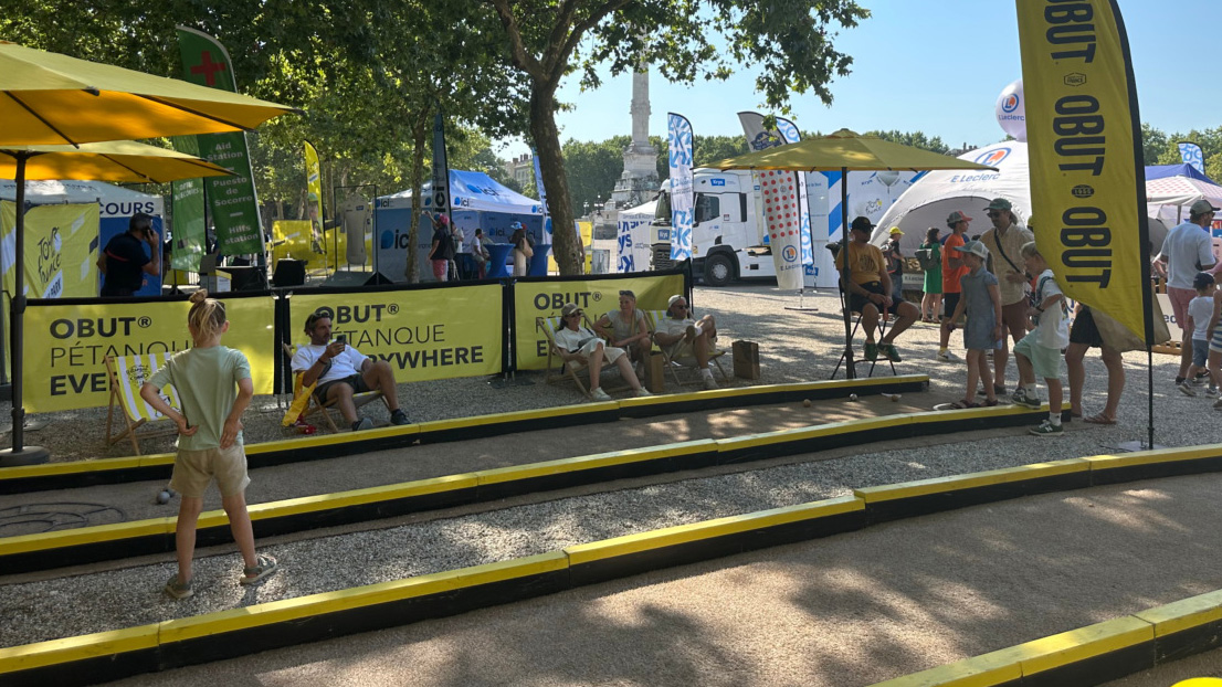 Una niña con otros visitantes en la pista de petanca Obut durante el Fan Park del Tour de Francia
