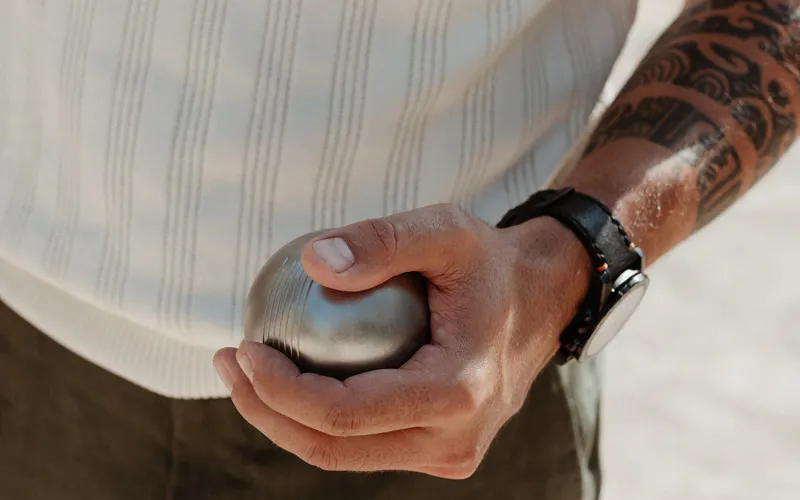 homme ayant une boule de pétanque dans la main