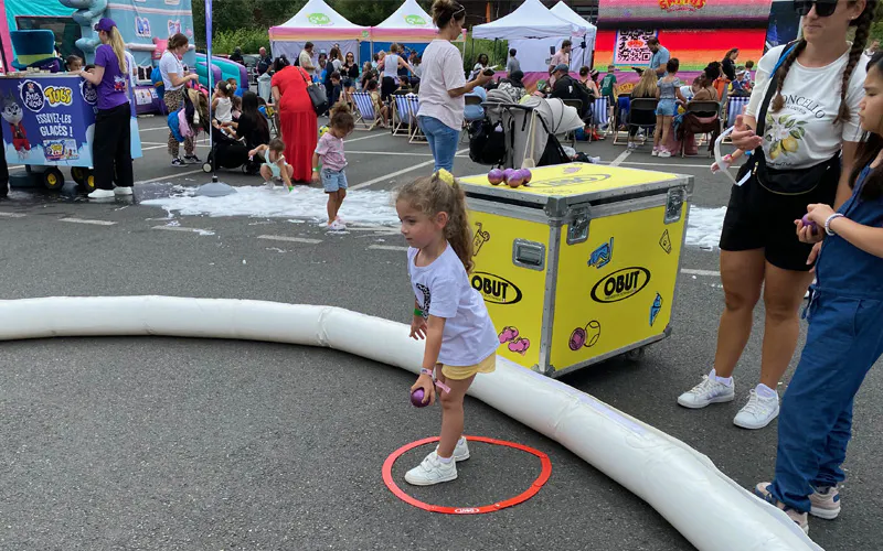 A young girl standing inside a pétanque throwing circle on a court set up for the Gulli Tour