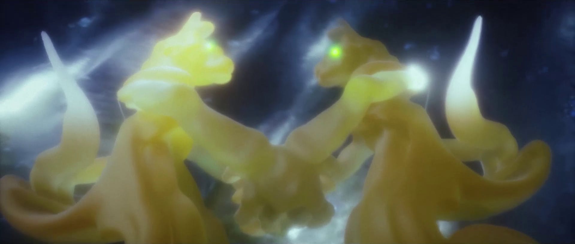 This is an abstract and ethereal image depicting what appears to be glowing, translucent figures in shades of yellow and white, with a dreamy, blurred quality. The central figure has a distinguishable green eye and seems to be gazing towards the other figure. The background is dark with hints of celestial bodies, suggesting a space-like or underwater setting. The overall effect is one of a serene, otherworldly encounter.