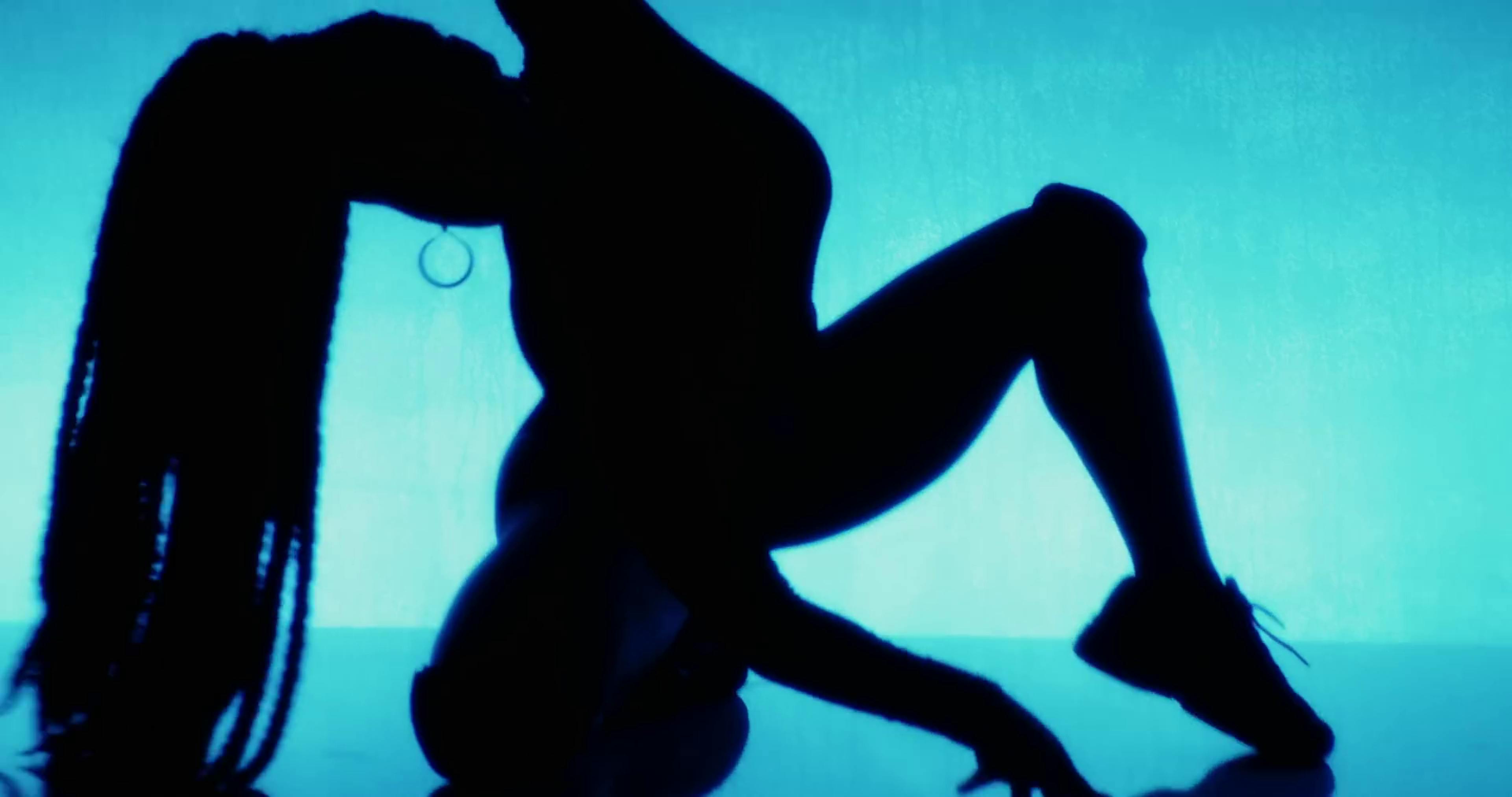 A silhouette of a woman against a blue background, dancing.
