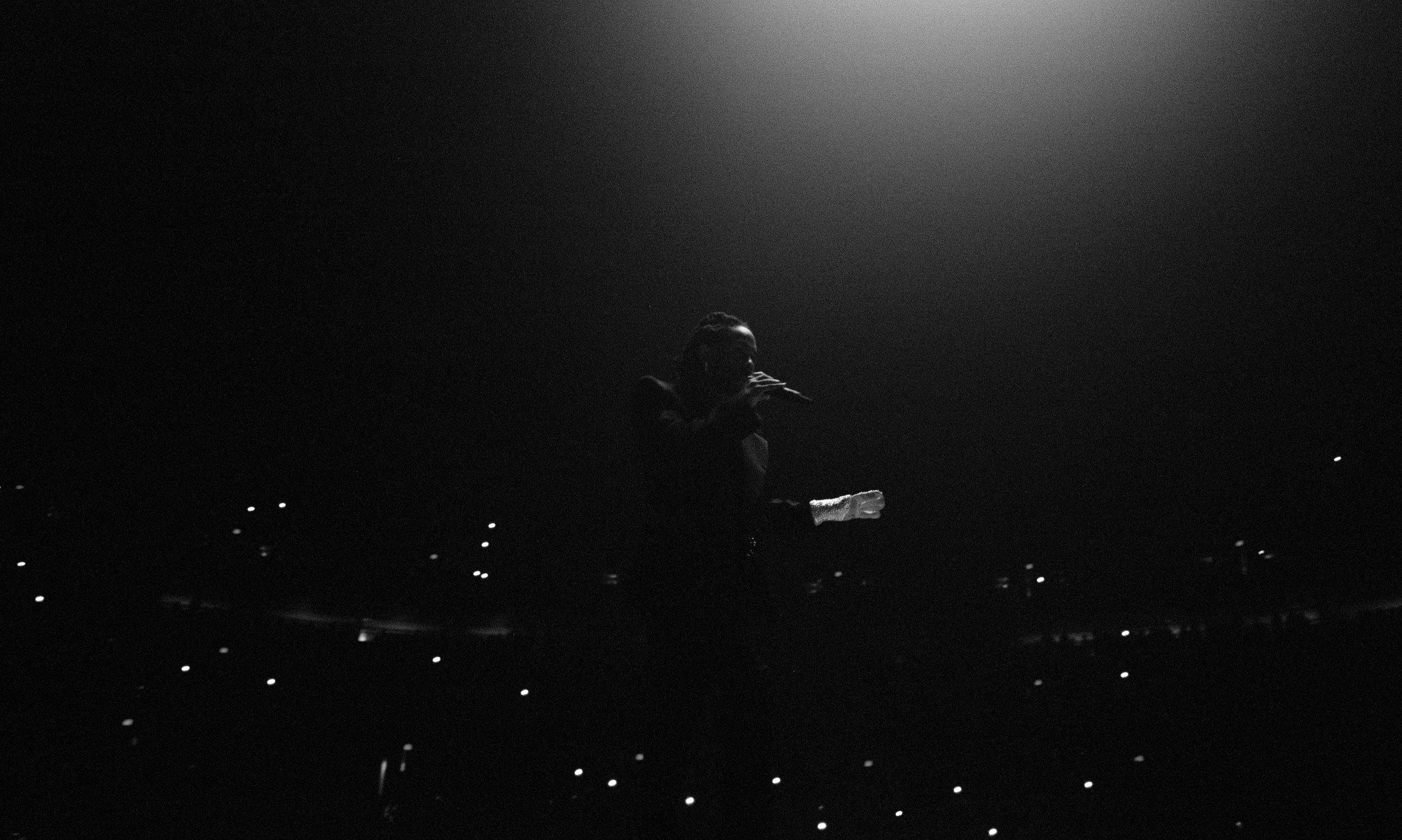 Kenrick Lamar perfomring on stage in a dimly lit environment