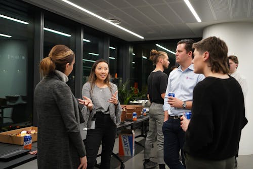A small group of people, inside and office space, talking. 