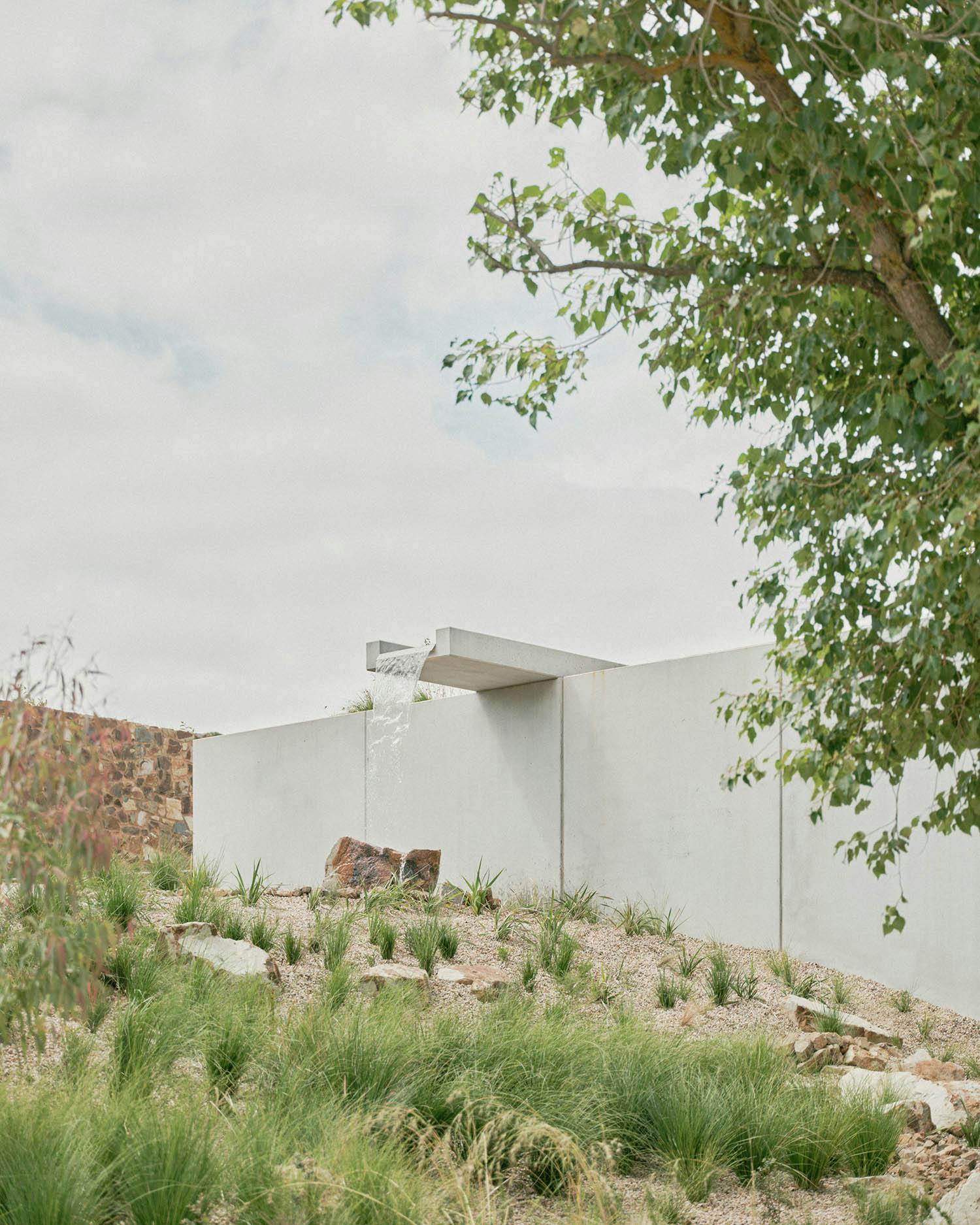 A photograph of a falling water feature. Waterflows onto a rock, set in a landscape filled with grasses. 