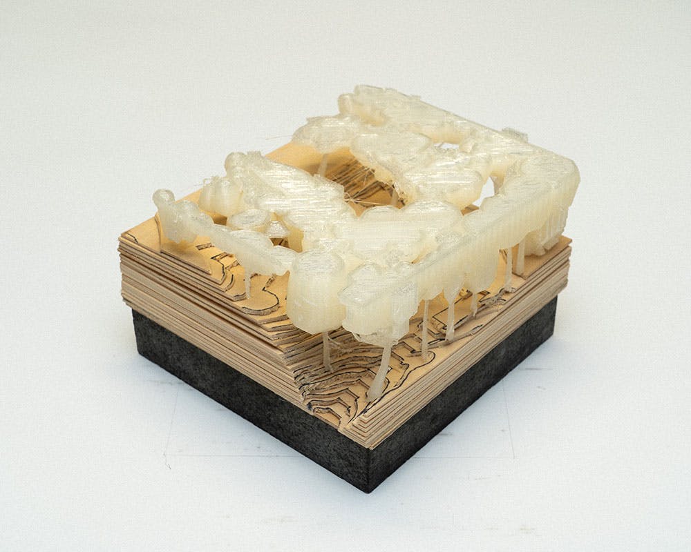 A photo of a small conceptual landscape model on a plywood base.