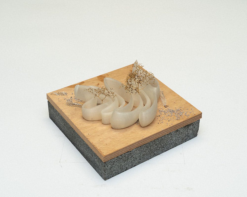 A photo of a small conceptual landscape model on a plywood base.