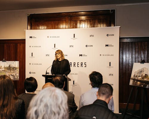 A photo of a person giving a speech in front of a media wall. 
