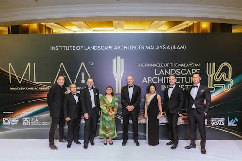 A photo of eight smiling people in formal attire, standing on a 'white carpet'