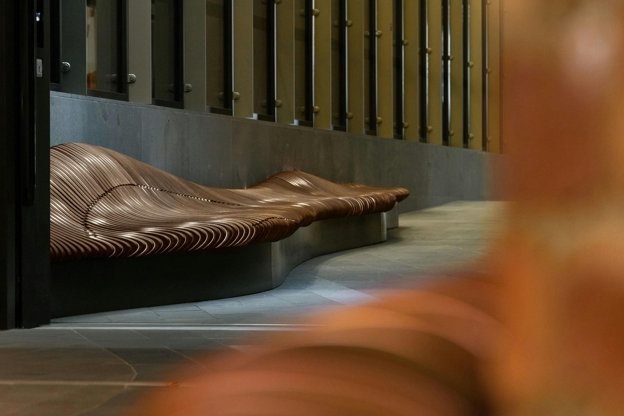 A photograph of two flowing parametric benches. They are wooden with glowing light from within.